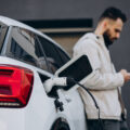 Man charging electric car by the house